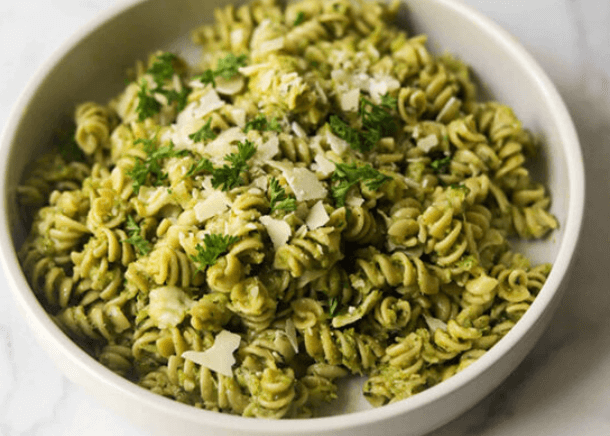 Spiral pasta with green sauce and shredded parmesan.