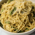 Spaghetti noodles with asparagus and white sauce.