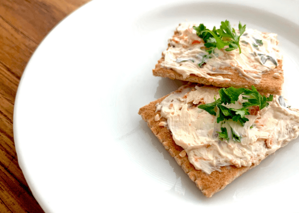 Cream cheese spread on crackers on a white plate.