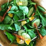 Spinach, cucumber, oranges, and red bell pepper salad.