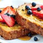 French toast with syrup, strawberries, and blueberries.