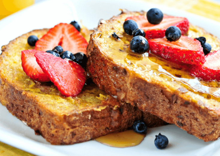 French toast with syrup, strawberries, and blueberries.