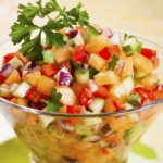 Diced peach, pineapple, and cucumber in a clear glass bowl.