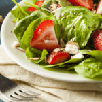 Strawberry, spinach, and feta salad on a plate with a fork.