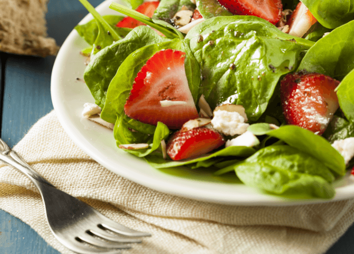 Strawberry, spinach, and feta salad on a plate with a fork.