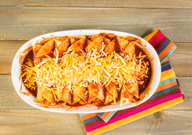 A white baking dish of enchiladas topped with cheese