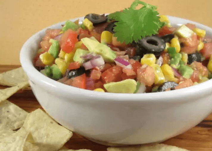 A bowl of tomato, corn avocado salsa garnished with cilantro