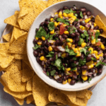 A bowl of black bean salsa surrounded by tortilla chips