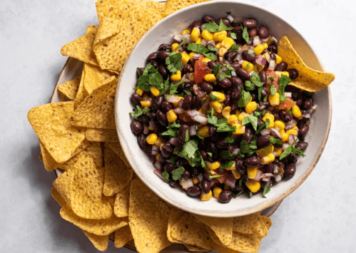 A bowl of black bean salsa surrounded by tortilla chips