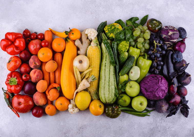 An assortment of fruits and vegetables arranged by color to match a rainbow