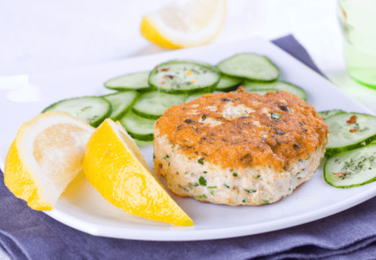 Lemon pepper salmon patties garnished with lemon and celery slices on a white plate