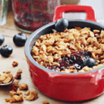 A red bowl of a blueberry and granola dessert