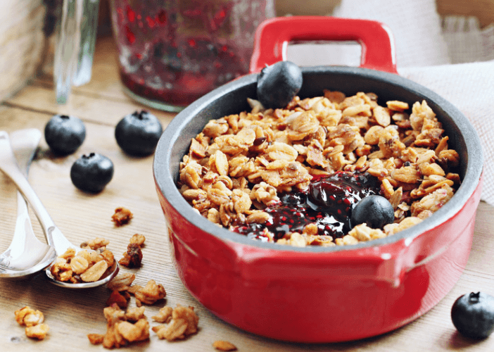 A red bowl of a blueberry and granola dessert