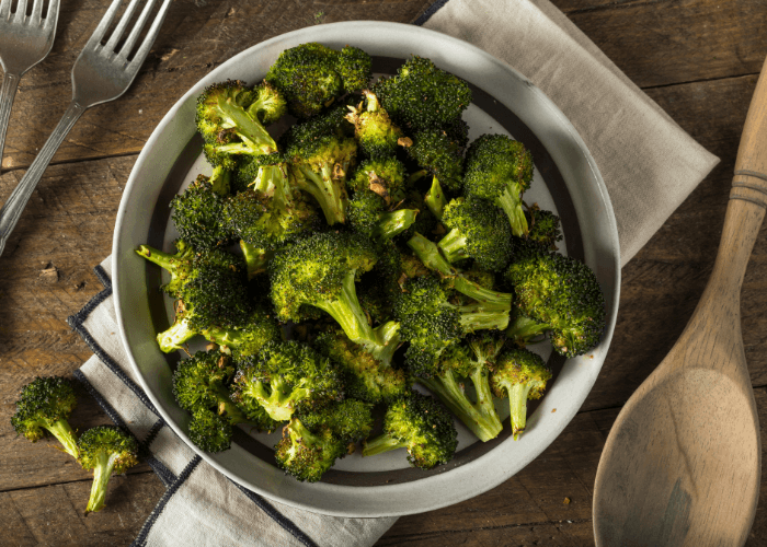 Roasted Broccoli in a bowl with utensils and napkin.