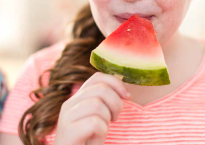 Child with a watermelon slice on a popsicle stick