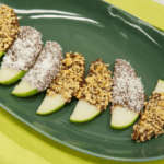 Apple slices dipped in chocolate with coconut and peanuts.