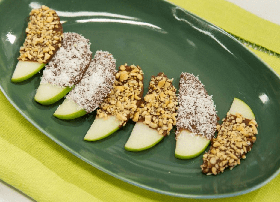 Apple slices dipped in chocolate with coconut and peanuts.