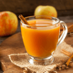 Apple orange cider in a mug with a cinnamon stick.