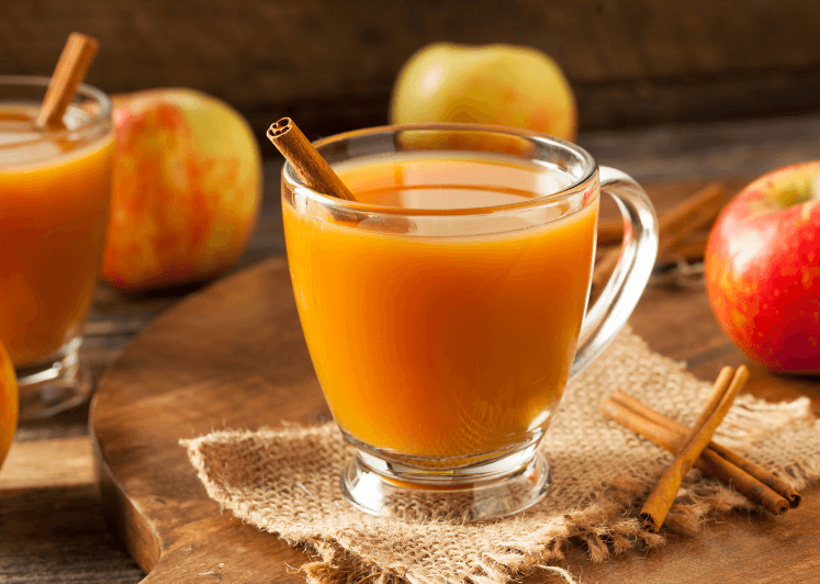 Apple orange cider in a mug with a cinnamon stick.