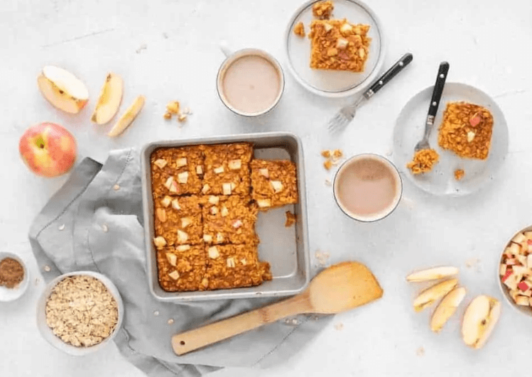 Apple baked oats in a baking dish surrounded by ingredients from the recipe
