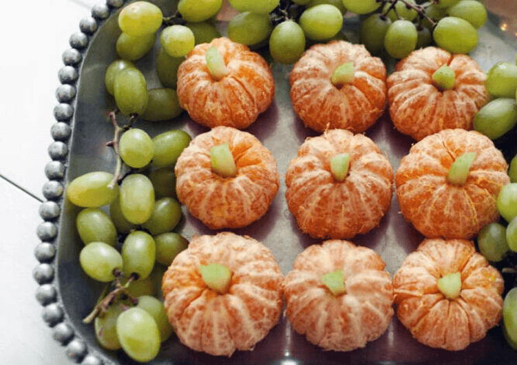 Oranges and grapes arranged as a pumpkin patch.