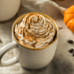 Pumpkin spice coffee in a mug along side of a pumpkin
