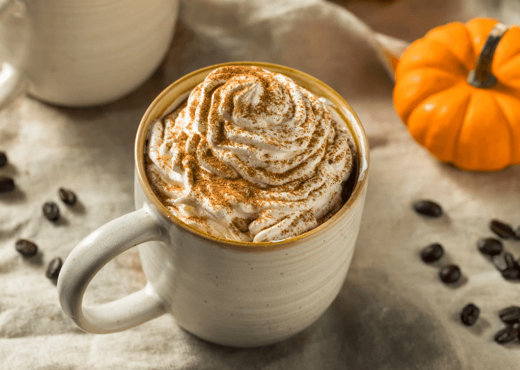 Pumpkin spice coffee in a mug along side of a pumpkin