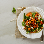 Sweet potato and arugula salad on a white plate