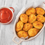 baked cauliflower tots in a dish with ketchup.