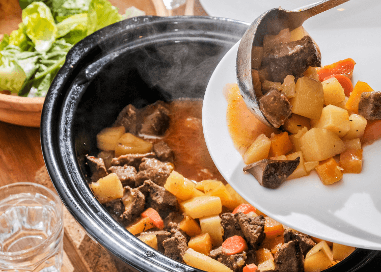 Potatoes and steak in a slow cooker.