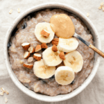 Oatmeal with sliced bananas and spoon with peanut butter