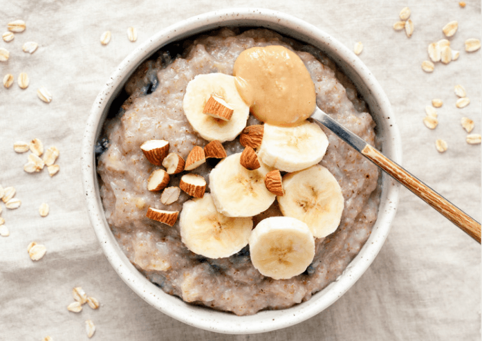 Oatmeal with sliced bananas and spoon with peanut butter