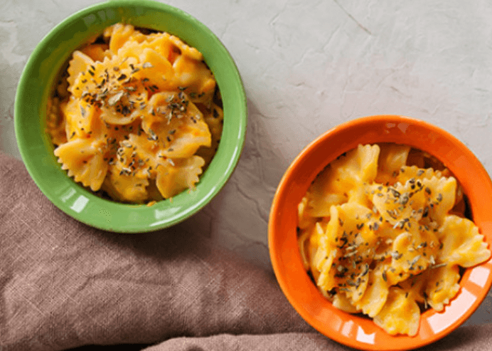 two bowls of pumpkin mac and cheese with herbs