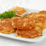 Several latkes on a plate with fresh herbs