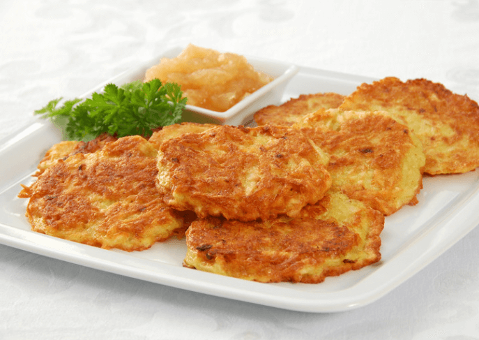 Several latkes on a plate with fresh herbs