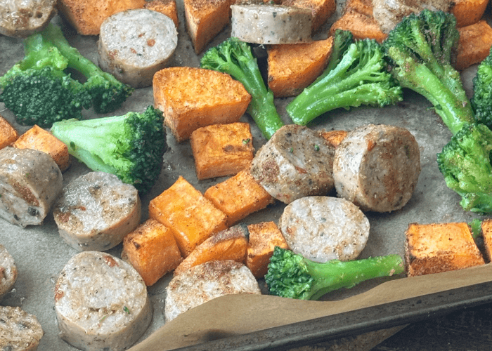 baking sheet with chopped sausage, broccoli florets, and diced sweet potato