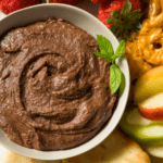 Chocolate Hummus served in a bowl with sliced apples and pretzels