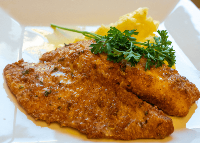 Crispy Parmesan Baked Fish topped with fresh herbs