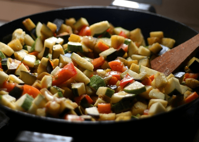 Vegetable stir fry in a cast iron pan with zucchini, squash, peppers