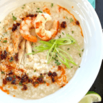 Shrimp & Chicken Congee in a bowl with a spoon & chopsticks