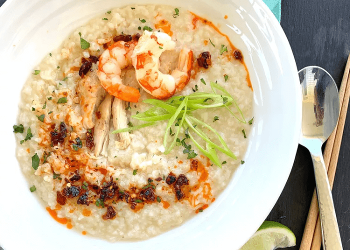 Shrimp & Chicken Congee in a bowl with a spoon & chopsticks