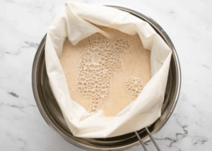 Oat milk in a cheesecloth draining liquid