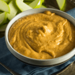 Pumpkin dip in a white bowl with diced apples