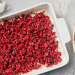 Cranberry Jalapeño Dip in a dish along side a plate of crackers