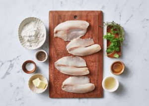 tilapia fillets on a cutting board with bowls of seasonings
