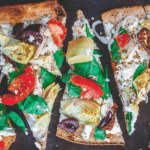 Flatbread pizza with feta cheese, tomatoes, spinach, artichoke hearts, olives, and shallot
