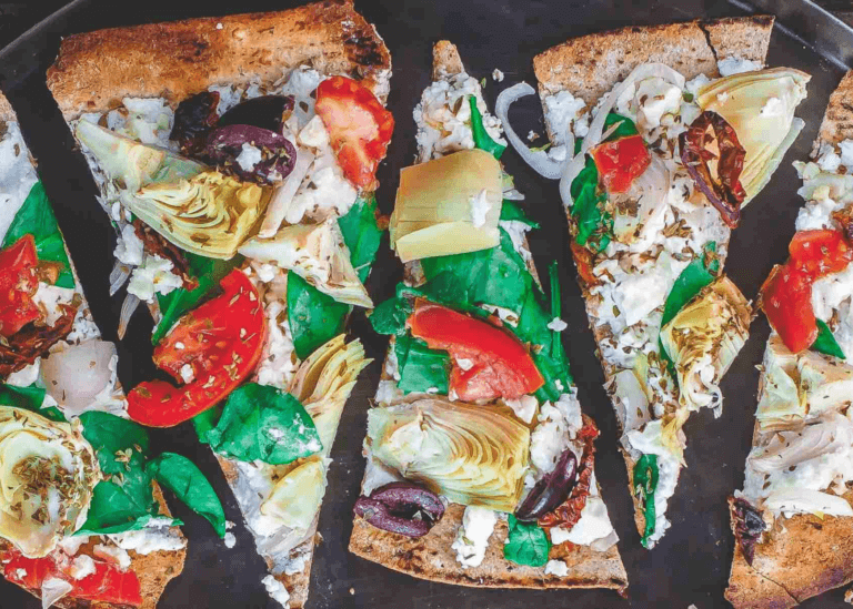 Flatbread pizza with feta cheese, tomatoes, spinach, artichoke hearts, olives, and shallot
